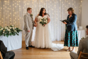 Bride and groom stand hand in hand looking serious during the ceremony